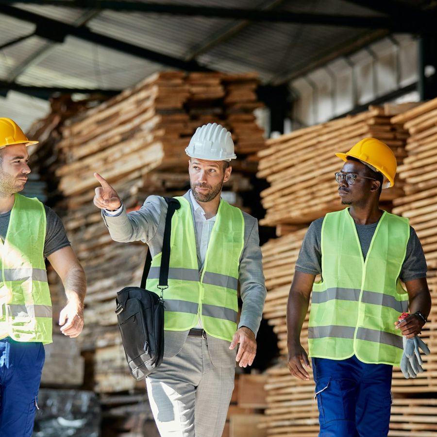 Wood warehouse owner communicating with employees while walking through storage compartment.